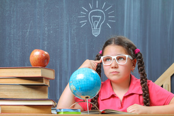 Happy school girl in front of the blackboard