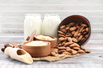 Almonds in bowl with bottles of milk on wooden table
