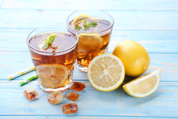 Ice tea in glasses with lemon and mint leafs on wooden table