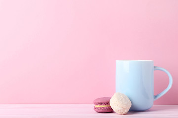 Cup of coffee with sweet macarons on pink background