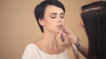 The make-up artist paints the eyes of the model with a pencil.