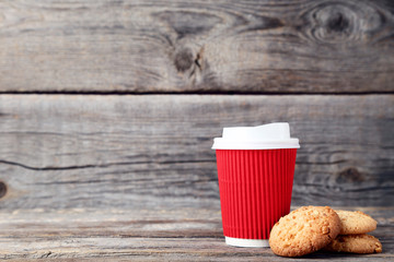 Paper cup of coffee with cookies on grey wooden table