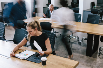 Businesswoman reviewing statistical reports in office
