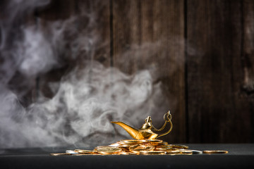 Magic lamp of wishes on stacks of gold coins with smoke coming out from the lamp. Studio shooting.