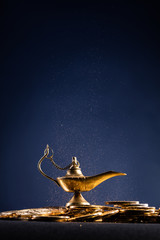 Magic lamp of wishes on stacks of gold coins with smoke coming out from the lamp. Studio shooting.