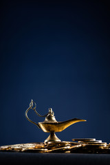 Magic lamp of wishes on stacks of gold coins with smoke coming out from the lamp. Studio shooting.
