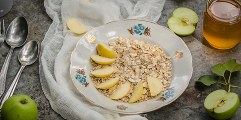 porridge - a portion a breakfast of oat flakes with honey, apples. food background