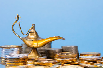 Magic lamp of wishes on stacks of gold coins. Studio shooting.