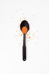 Flat lay of arranged black plastic spoon with flax seeds on white background.