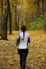 Image from back in full growth of girl running along autumn foliage