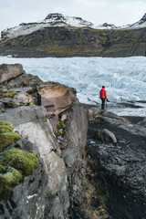 A man in a red jacket looks at the glacier in Iceland Svinafellsjokull