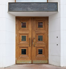 Obraz na płótnie Canvas A wooden oak door of a public building with a large metal plaque at the top.