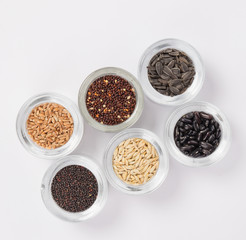 Top view of different seeds in glass glasses on a white background