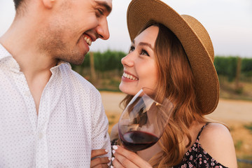 Loving couple outdoors holding glasses of wine.