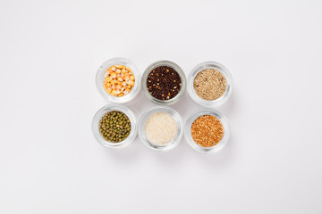 Top view of different seeds in glass glasses on a white background