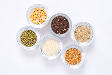 Top view of different seeds in glass glasses on a white background