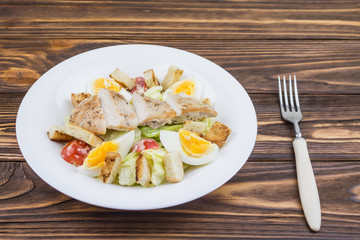 Caesar salad with chicken, on a wooden background