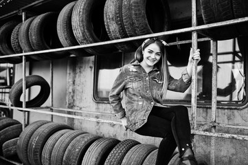 Young hipster girl in jeans jacket and head scarf at tire fitting zone.