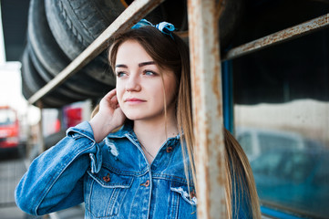 Young hipster girl in jeans jacket and head scarf at tire fitting zone.