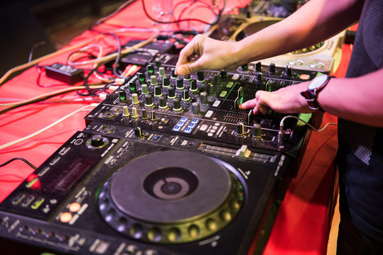 Dj mixes the track in the nightclub at party, hand playing music at turntable on party