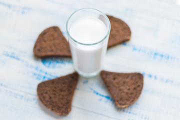 A glass of milk, kefir and a slice of black bread on a wooden background. The concept of healthy nutrition, diet.