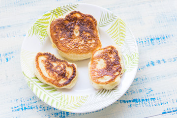 Delicious fritters, pancakes on a plate on a wooden background.