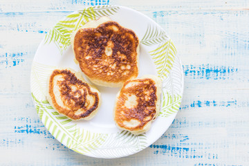 Delicious fritters, pancakes on a plate on a wooden background.