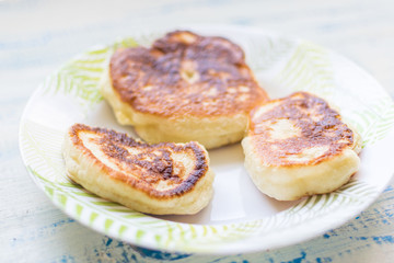 Delicious fritters, pancakes on a plate on a wooden background.