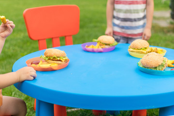Sandwiches, hamburgers and French fries are served on a blue table for children.