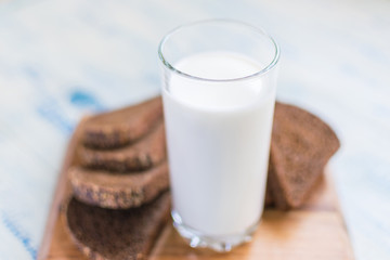 A glass of milk, kefir and a slice of black bread on a wooden background. The concept of healthy...