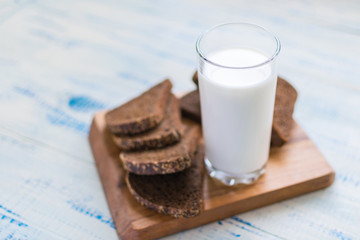 A glass of milk, kefir and a slice of black bread on a wooden background. The concept of healthy nutrition, diet.
