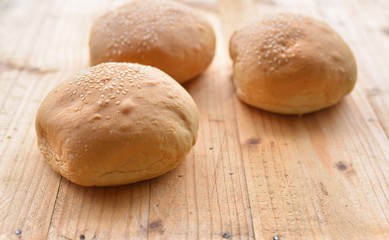 uncut burger buns on wooden table.