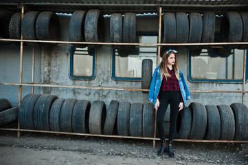 Young hipster girl in jeans jacket and head scarf at tire fitting zone.