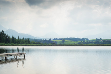 Steg am See in den Bergen am Tag mit Wolken im Sommer
