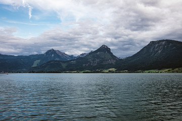 Lake called Wolfgangsee in Austria with mountian in the background and clouds on the sky