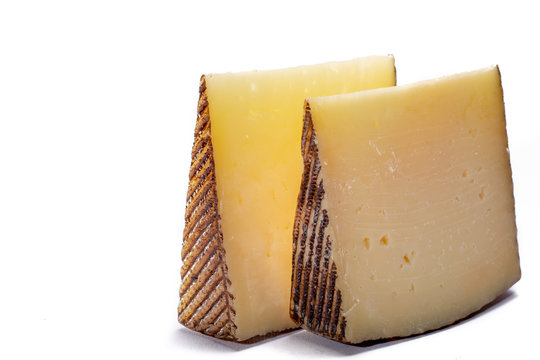 Two pieces of Manchego, queso manchego, cheese made in La Mancha region of Spain from the milk of sheep of the manchega breed, isolated on white