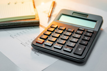 Calculator, pen, blank lined paper page of notebook and summary report paperwork with bar graph and table. Financial data analysis. Business planning and management concept