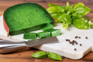 Piece of green pesto hard Dutch cheese made with fresh basil herb, garlic and onion