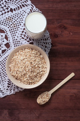 Oatmeal milk, bowl with oatmeal on the wooden table. Healthy living.
