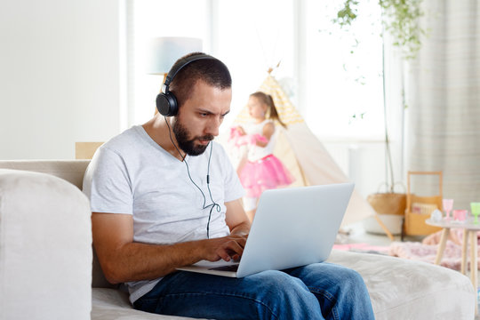 Busy young father working on laptop at home - Powered by Adobe