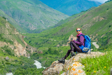 Fototapeta premium Young woman in the mountains with a backpack. Mountain landscape. River in the valley.