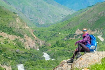 Young woman in the mountains with a backpack. Mountain landscape. River in the valley.