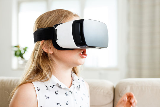 Excited girl using virtual reality goggle at home