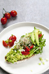 Rye toast with avocado, tomatoes and alfalfa sprouts
