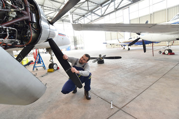 Mechaniker kontrolliert und repariert Flugzeug im Hangar // Airport workers check an aircraft for...