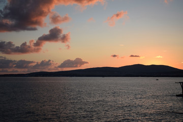 Sunset over the sea. The Sun sets behind the mountains