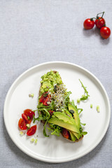 Rye toast with avocado, tomatoes and alfalfa sprouts