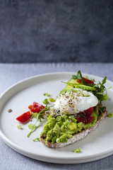 Rye toast with avocado, tomatoes, alfalfa sprouts and poached egg
