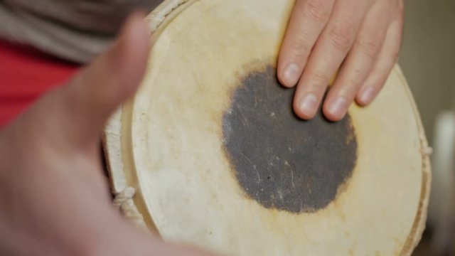 Close up of hands of a man playing a drum.