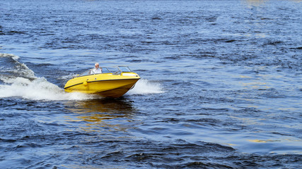 A yellow pleasure boat sails along the canals of the city of St. Petersburg, Russia.